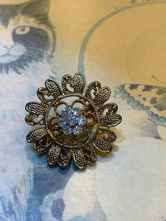 Broche dourado em formato de flor com strass